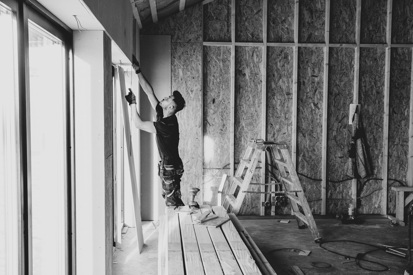 Un homme pose une plaque de plâtre sur un mur dans un bâtiment.