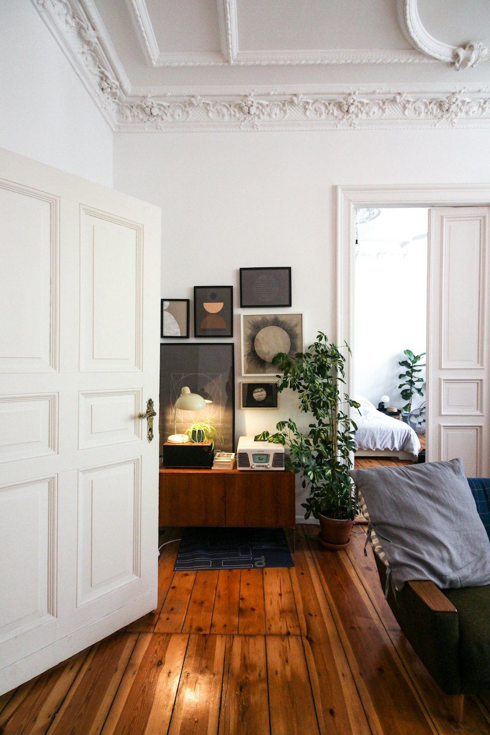 Salon d'appartement confortable avec mur de cadres et plantes.