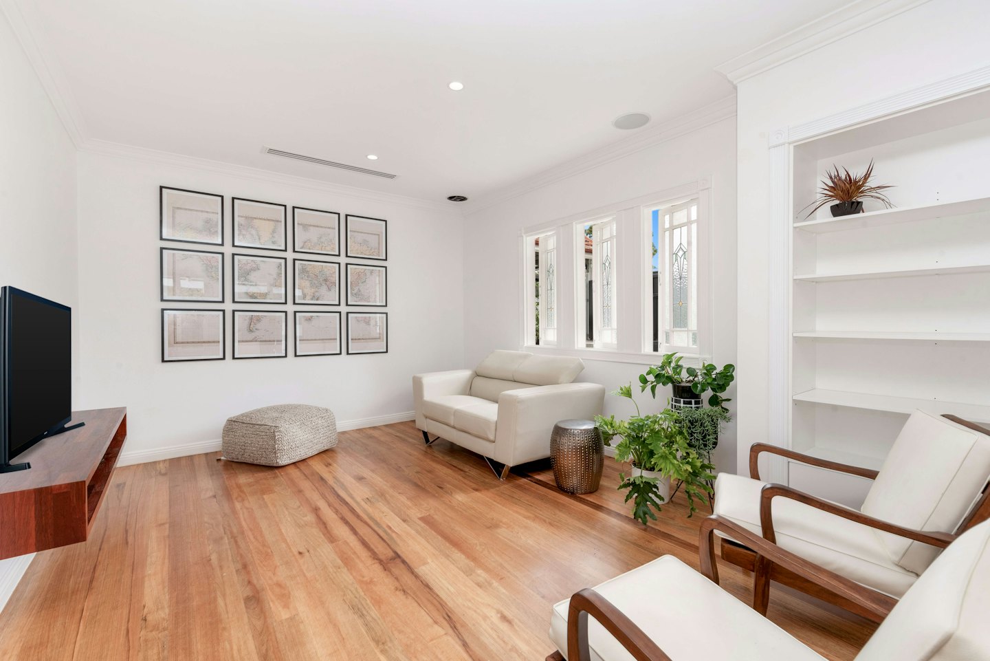 Salon moderne avec canapé crème, fauteuils et impressions de cartes.