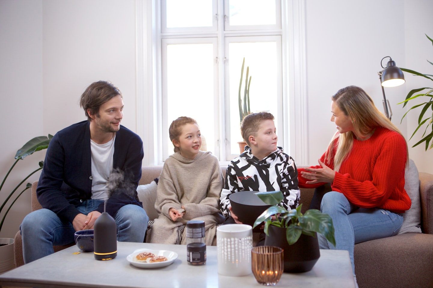 Une famille assise sur un canapé discute dans le salon.
