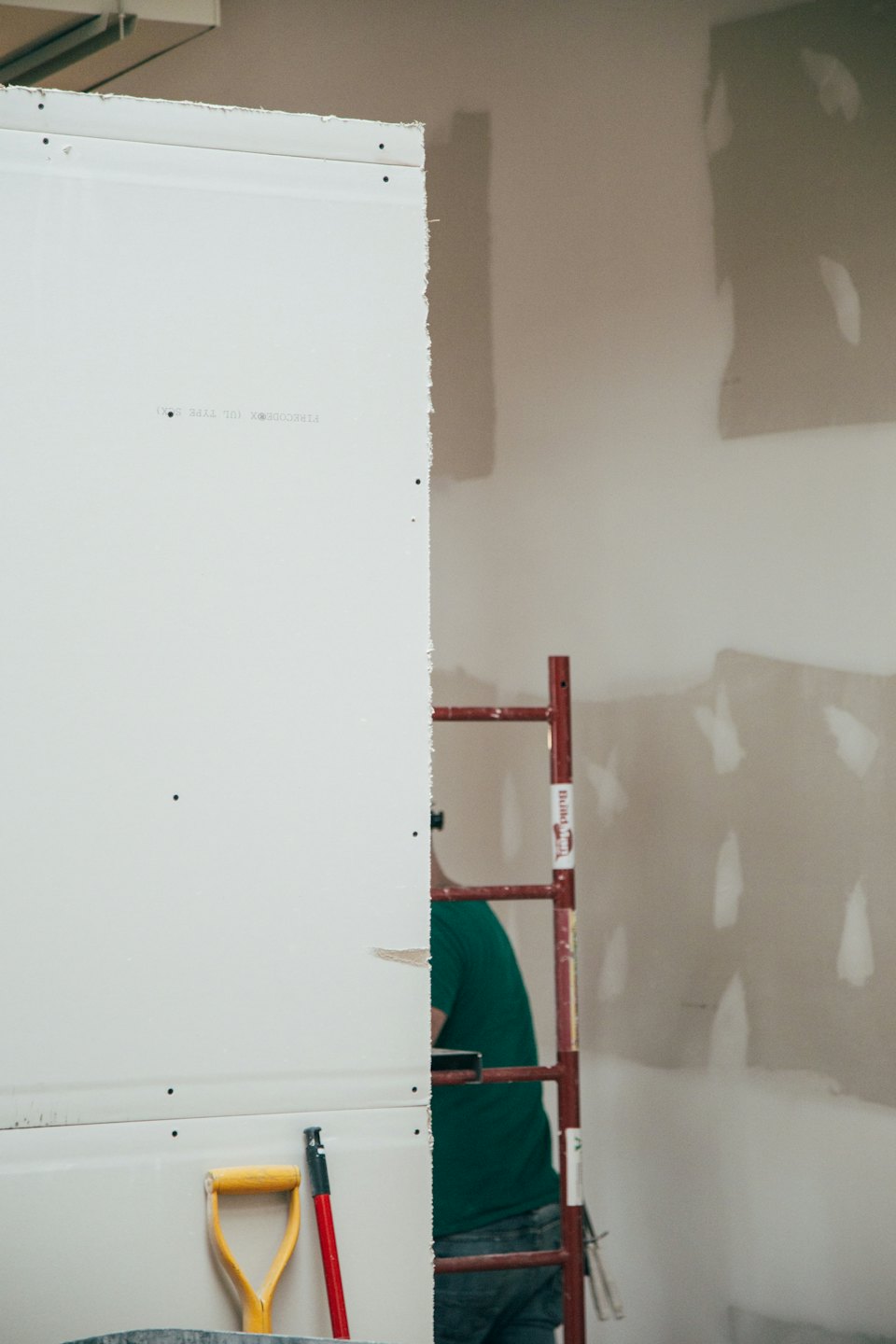 Un ouvrier du bâtiment installe des cloisons sèches dans une nouvelle pièce intérieure.