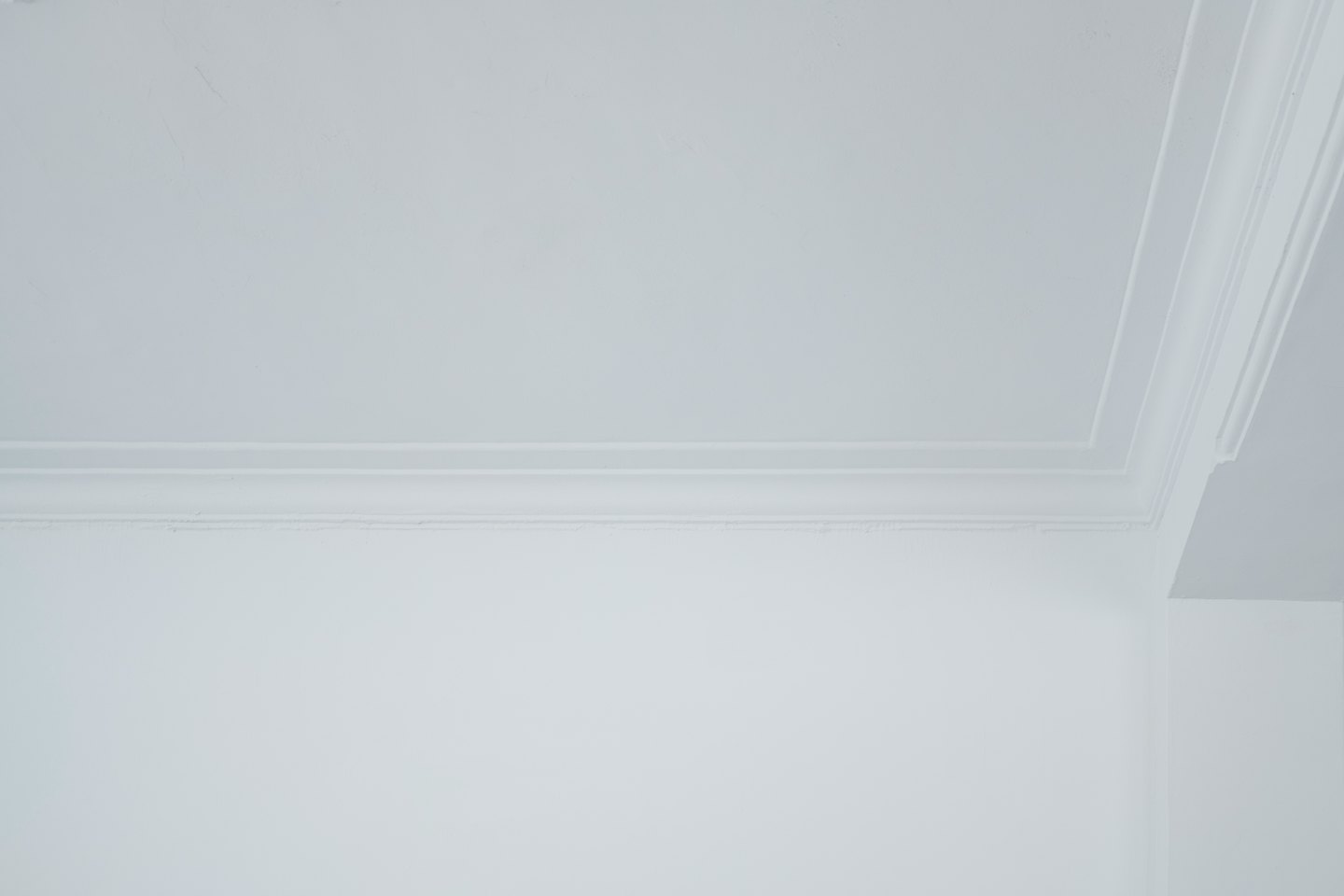 Corniche blanche ornée installée dans un coin de plafond.