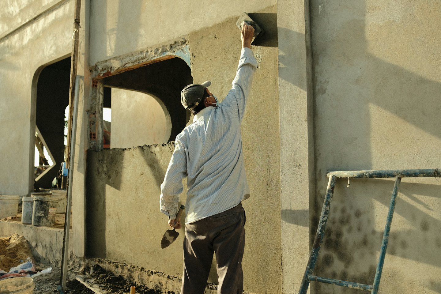 Un ouvrier du bâtiment enduisant la façade d'un immeuble.